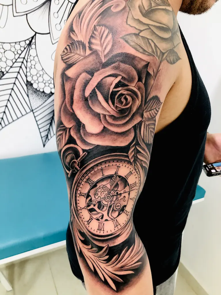 tatuaje en el brazo de una rosa con un reloj