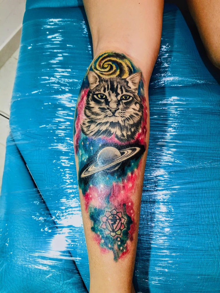tatuaje en pantorilla de un gato con fondo multicolor